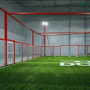 Interior view of a professional soccer cage highlighting the artificial turf and tempered glass panels