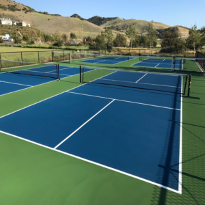 Newly built pickleball court complex with blue-green LDK flooring and regulation nets, ready for play