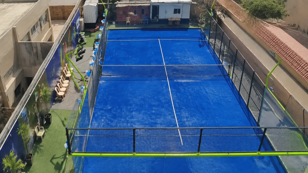 full panoramic padel court overview uae Elevated overview of a blue panoramic padel court in an urban site